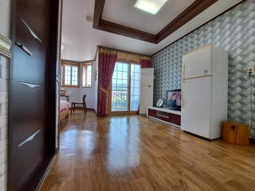 a large living room with a white refrigerator in it at Beljari Pension in Tongyeong