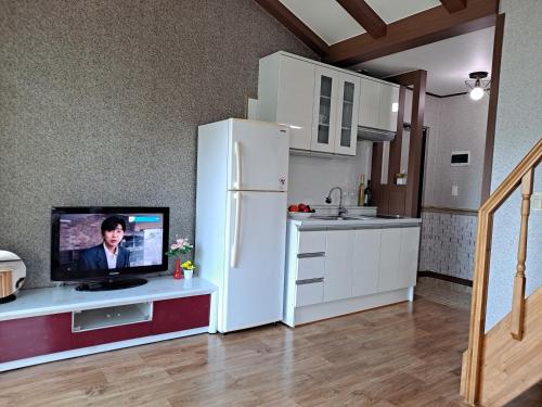 a kitchen with a refrigerator and a tv on a counter at Beljari Pension in Tongyeong