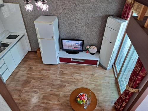 a kitchen with a refrigerator and a table with a television at Beljari Pension in Tongyeong