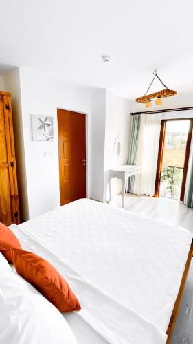 a bedroom with a large white bed with orange pillows at Pupa Alaçatı Butik Otel in Cesme