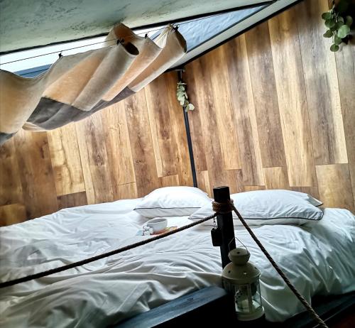 a bed in a room with a wooden wall at Tripsylvania Tiny House in Şirnea
