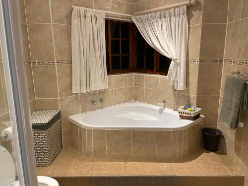 a bath tub in a bathroom with a window at Boikhutsong House in Mbabane