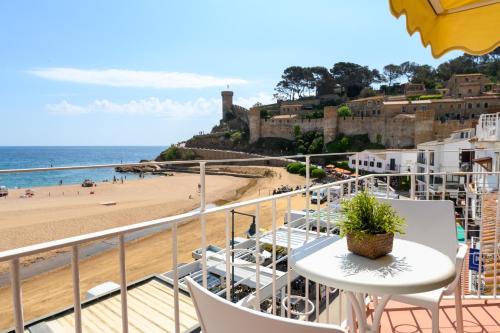 uma varanda com uma mesa e cadeiras e uma praia em Hotel Capri em Tossa de Mar