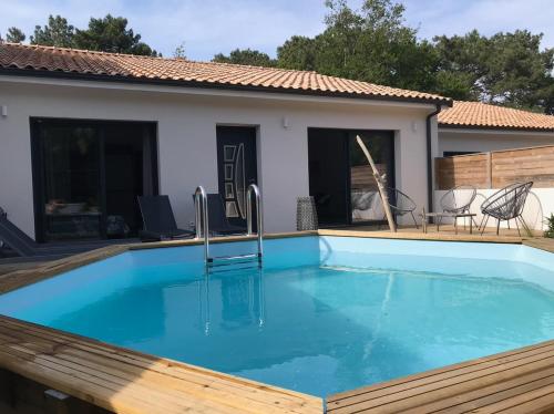 une piscine avec une terrasse en bois et une maison dans l'établissement Du sable et des pins, au Le Verdon-sur-Mer