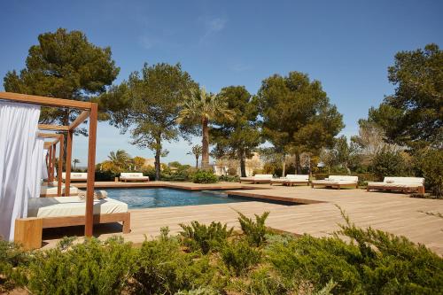 un patio trasero con piscina y terraza de madera en Fontsanta Hotel Thermal & Spa - Adults Only en Colonia Sant Jordi