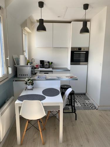 a white kitchen with a table and chairs in it at Appartement Design V Port de Tréboul-Douarnenez in Douarnenez