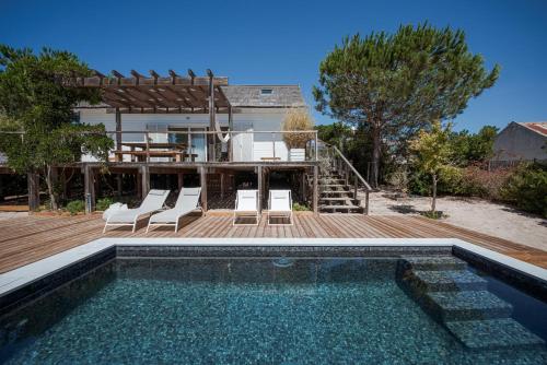 a swimming pool on a wooden deck next to a house at Precious Cabin in Comporta in Comporta
