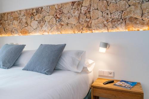a bedroom with a bed with a stone wall above it at Hotel S'Antiga Adults Only in Es Mercadal