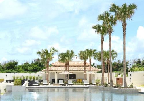 a villa with palm trees and a swimming pool at Hotel Monterey Okinawa Spa & Resort in Onna