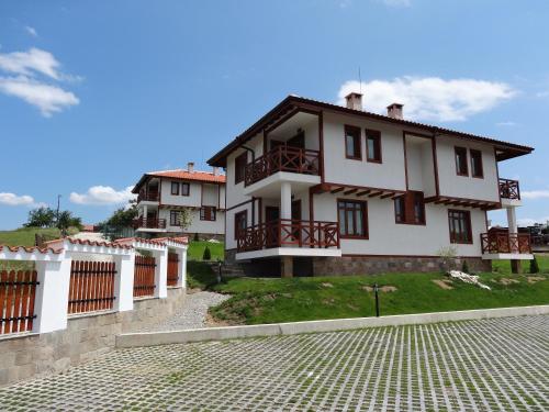 a large white house with a cobblestone street at Guest House Ivanini Houses in Tryavna