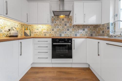 una cocina blanca con armarios blancos y fregadero en Cheerful Stays - Livingston - 4 Bedroom 3 Bath home, en Livingston
