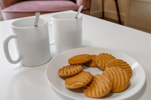 a plate of cookies on a table next to two mugs at Cheerful Stays - Livingston - 4 Bedroom 3 Bath home in Livingston
