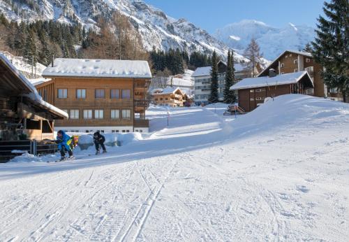 two people on skis in the snow near a ski lodge at Chalet Stella Duplex Penthouse in Wengen