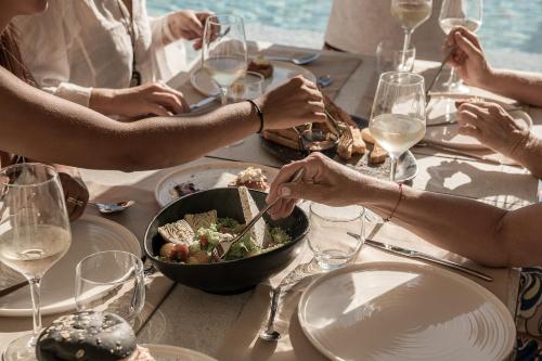 a group of people sitting around a table with a bowl of food at Mossa Well Being Hotel - Heated pool in Kato Daratso