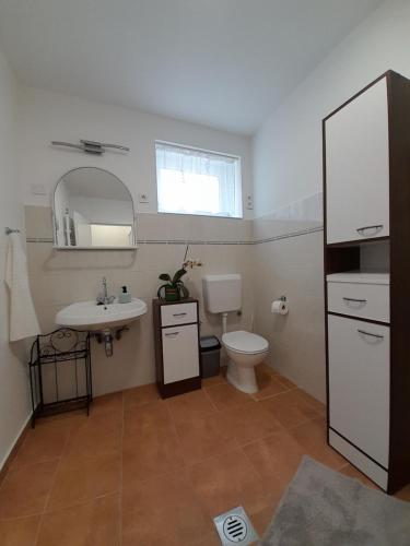 a bathroom with a toilet and a sink and a mirror at Déri Kert Apartmanház A in Baja