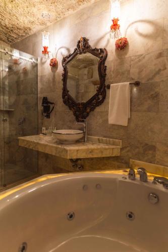 a bathroom with a tub and a sink and a mirror at Solo Cave Suites in Nevsehir
