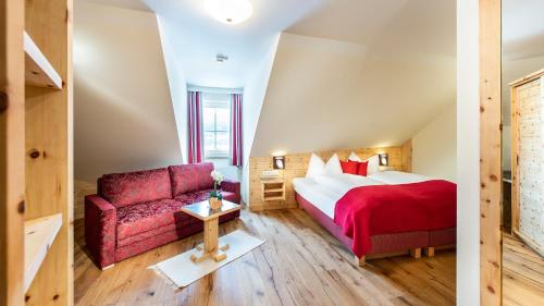 a bedroom with a bed and a red couch at Grizzly Sport & Motorrad Resort in Sankt Margarethen im Lungau