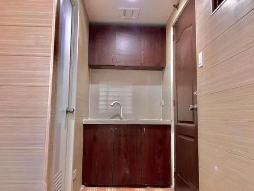 a bathroom with a sink and a wooden door at Maine City Residences Leveriza in Manila