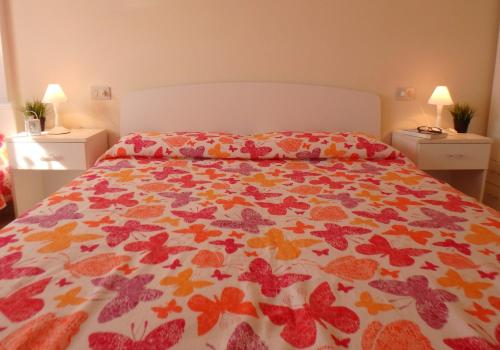 1 dormitorio con 1 cama con colcha colorida con mariposas en Montebianco 30 en Lido di Pomposa