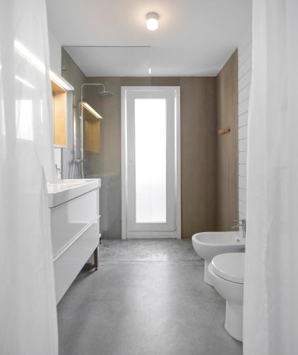 a bathroom with two sinks and a toilet and a door at Precious Cabin in Comporta in Comporta