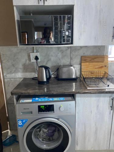 a kitchen with a washing machine under a counter at RCB guesthouse in Burgersfort