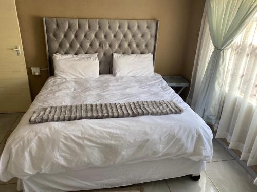 a white bed with a large headboard and white sheets at RCB guesthouse in Burgersfort
