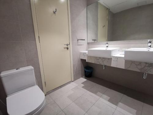 a bathroom with two sinks and a toilet and a mirror at The Ooak Suites and Residence@ Kiara 163 in Kuala Lumpur