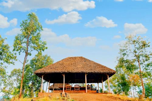 a pavilion with a straw roof on a field at Sextantio Rwanda, The Capanne (Huts) Project in Kamembe