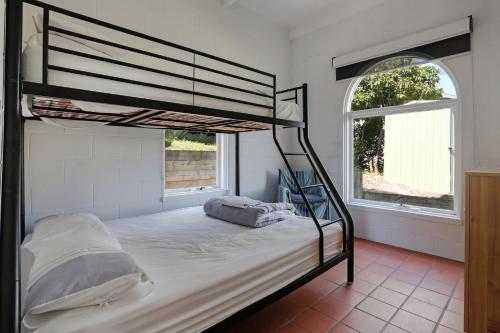 a bedroom with a bunk bed in a room with two windows at Cordova - Perfect Summer or Winter Getaway in Merimbula