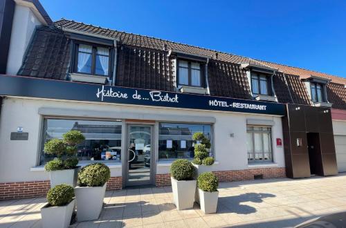 un magasin devant un bâtiment avec des plantes devant dans l'établissement Hôtel - Restaurant "Histoire de Bistrot", à Isbergues