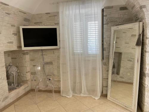 Habitación con TV, silla y espejo. en B&B RESORT SIGNORILE, en Bari