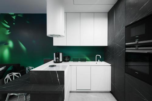 a kitchen with white cabinets and a green wall at Apartamenty Oliwia - Kącik in Krakow