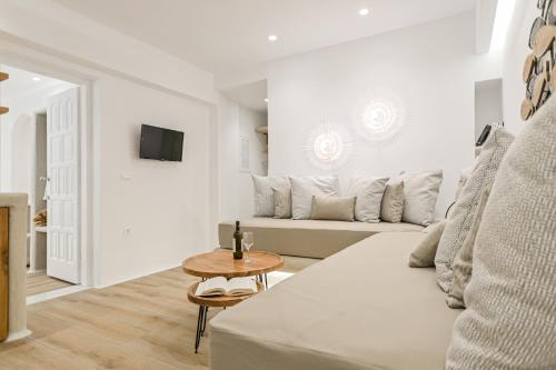 a white living room with a couch and a table at Villa Adriana Hotel in Agios Prokopios
