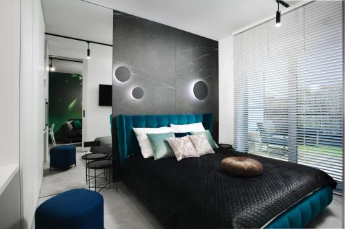 Apartamenty Oliwia - Kącik في كراكوف: غرفة نوم مع سرير أسود مع اللوح الأمامي الأزرق