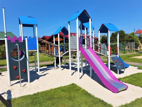 a playground with a slide in the sand at WIR Gąski - domki letniskowe in Gąski