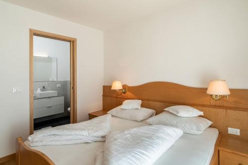 a bedroom with a bed with white pillows and a mirror at Pension Grafenau in Schenna