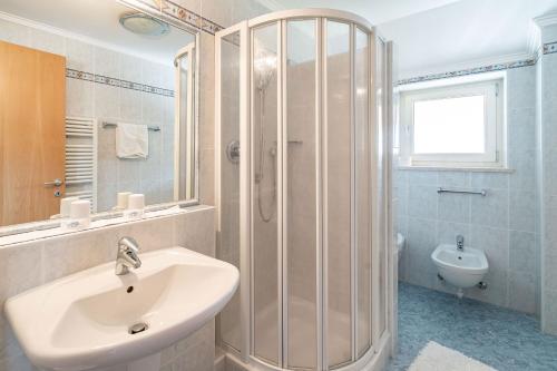 a bathroom with a sink and a shower and a toilet at Pension Grafenau in Schenna