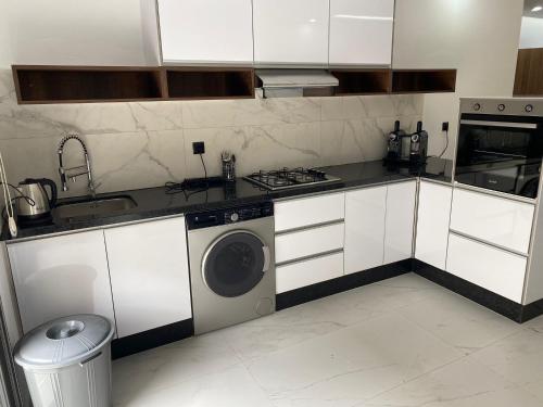 a kitchen with white cabinets and a washing machine at Iquama atawhid I in Nador