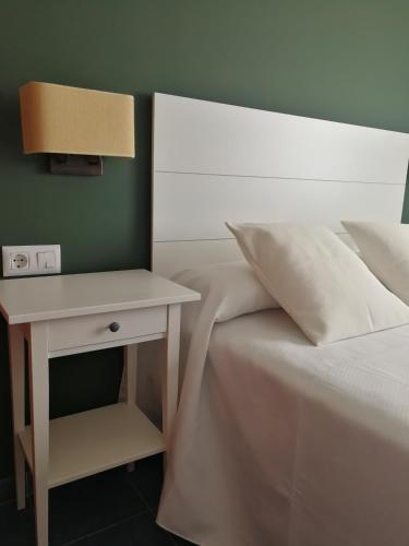 a bed with a nightstand next to a white bed with a lamp at PENSION CASA JULIO ** in Culleredo