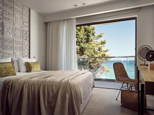 een slaapkamer met een bed en een groot raam bij Windmill Bay Hotel in Argassi