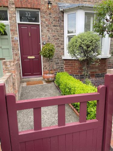 a red wooden fence in front of a house at Period two-bed house, next to river and city in York