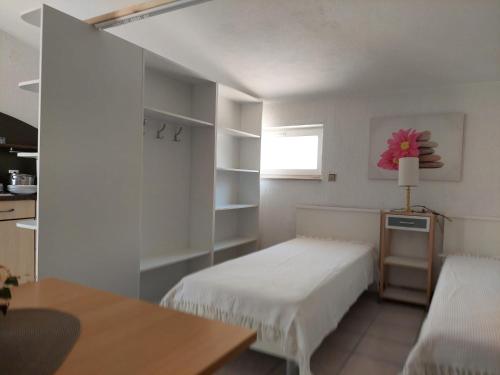 1 dormitorio con 2 camas, mesa y ventana en House Bilic en Baška Voda