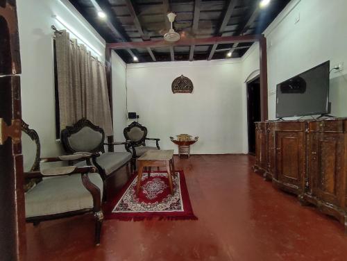 a living room with a tv and a chair and a table at SuKun Heritage in Kannur