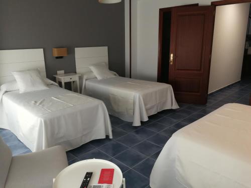 a hotel room with two beds and a remote control at PENSION CASA JULIO ** in Culleredo
