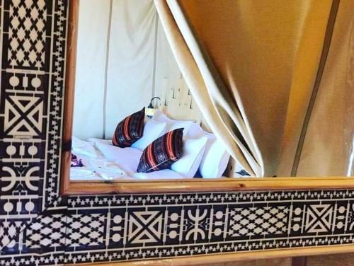 a reflection of a bed with pillows in a mirror at desert camp sahara luxury in Merzouga