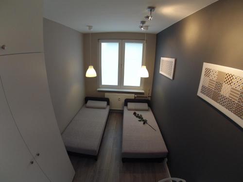 a small room with two beds and a window at Apartamenty w centrum Gdyni I in Gdynia