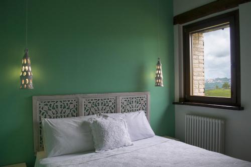 a green bedroom with a bed and a window at Fattoria Bio L'A Ceccoli in Sassofeltrio