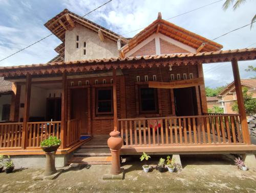 een huis met een veranda en een terras bij Romadhoni Homestay in Magelang