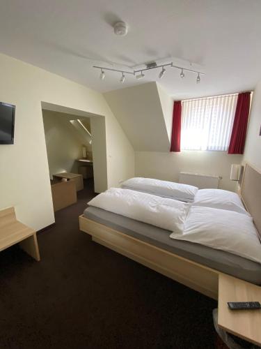 a bedroom with a large bed with white sheets at Hotel Alt Westerholt in Herten