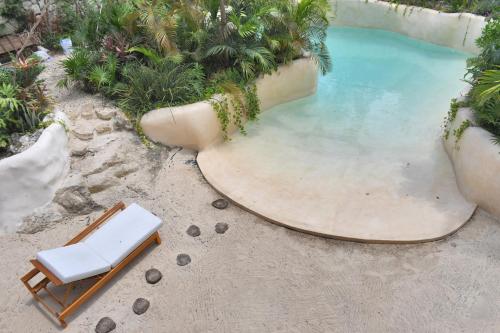 uma piscina com uma espreguiçadeira e uma piscina em IIK Tulum Luxury Condo by Spot Rentals em Tulum